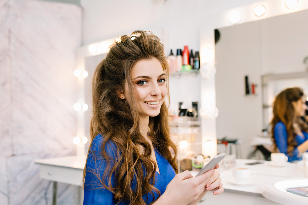 Exploring the digital age of scheduling right at her fingertips! A salon customer easily books her next appointment using an efficient online system, showcasing the power and convenience of high conversion online scheduling.